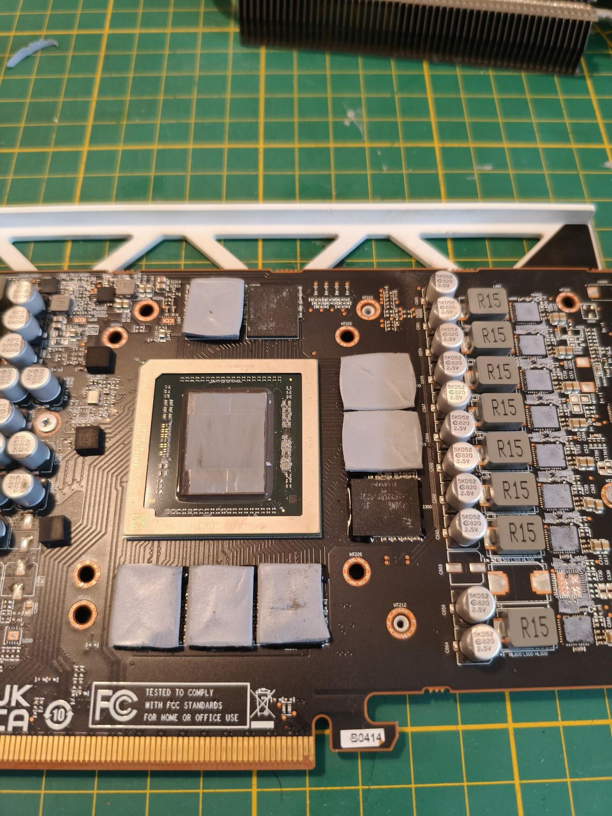 GPU PCB close-up — die con pasta termica secca e pad VRAM vecchi prima della sostituzione